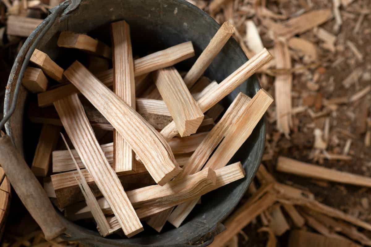 Image of a metal bucket filled with thin wooden kindling sticks for starting a fire pit.