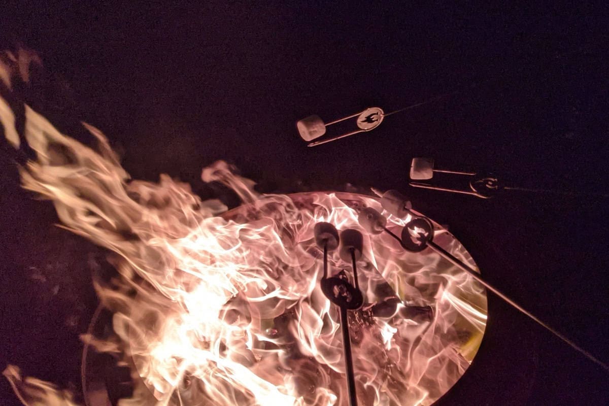 Image of marshmallow roasting over fire pit at night.