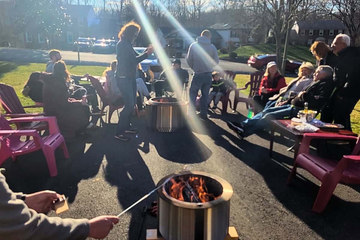 Image of a group of people around two fire pits on a driveway for a blog post covering the benefits of a fire pit.