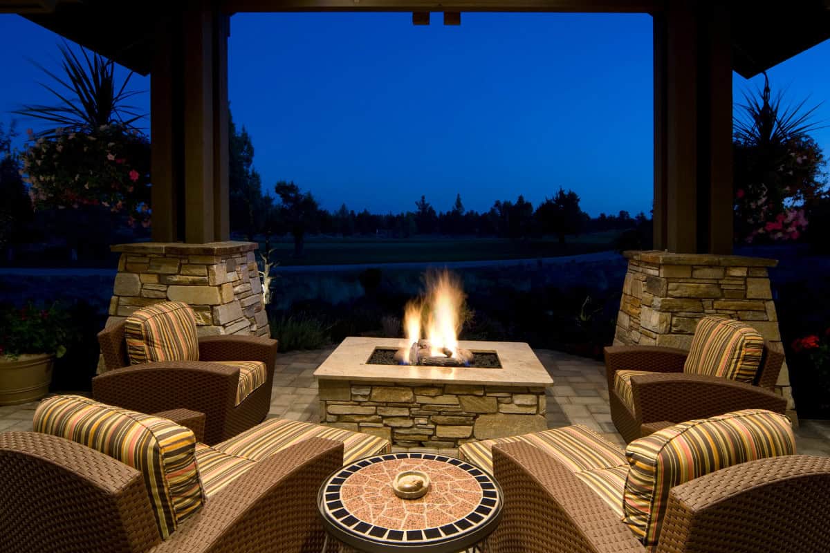 Image of a fixed gas fire pit and four chairs on the corners.