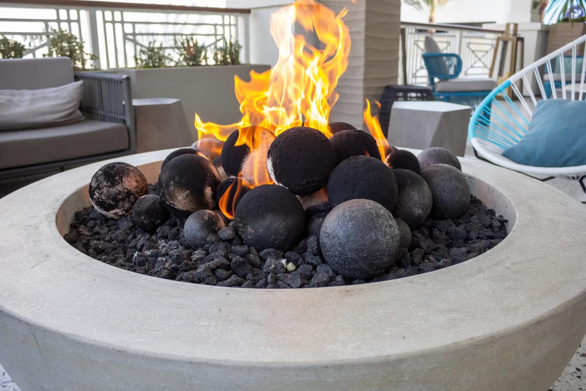 Image of a round gas fire pit with large round fire pit media added.
