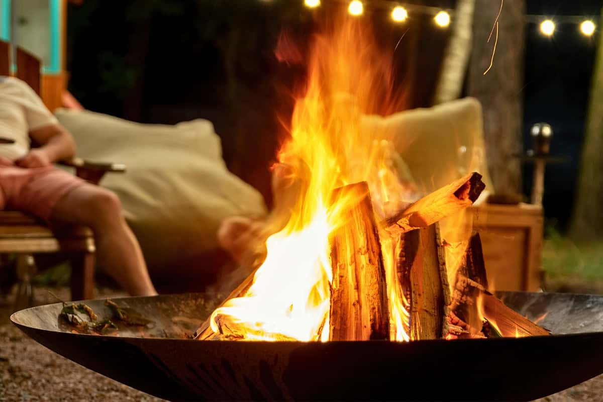 Image of a fire pit bowl burning at night for a blog post covering the benefits of a fire pit.
