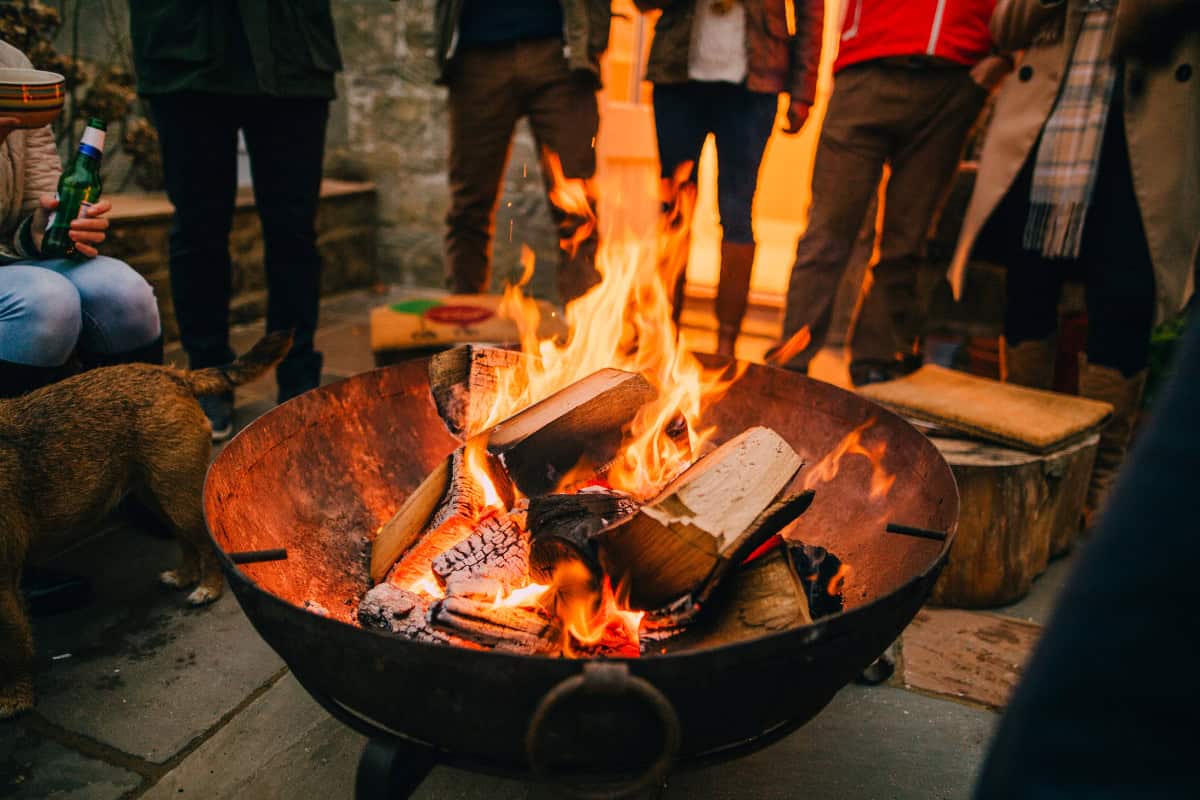 Image of a group of people around a burning fire pit for a blog post answering the question "is a fire pit open burning?"