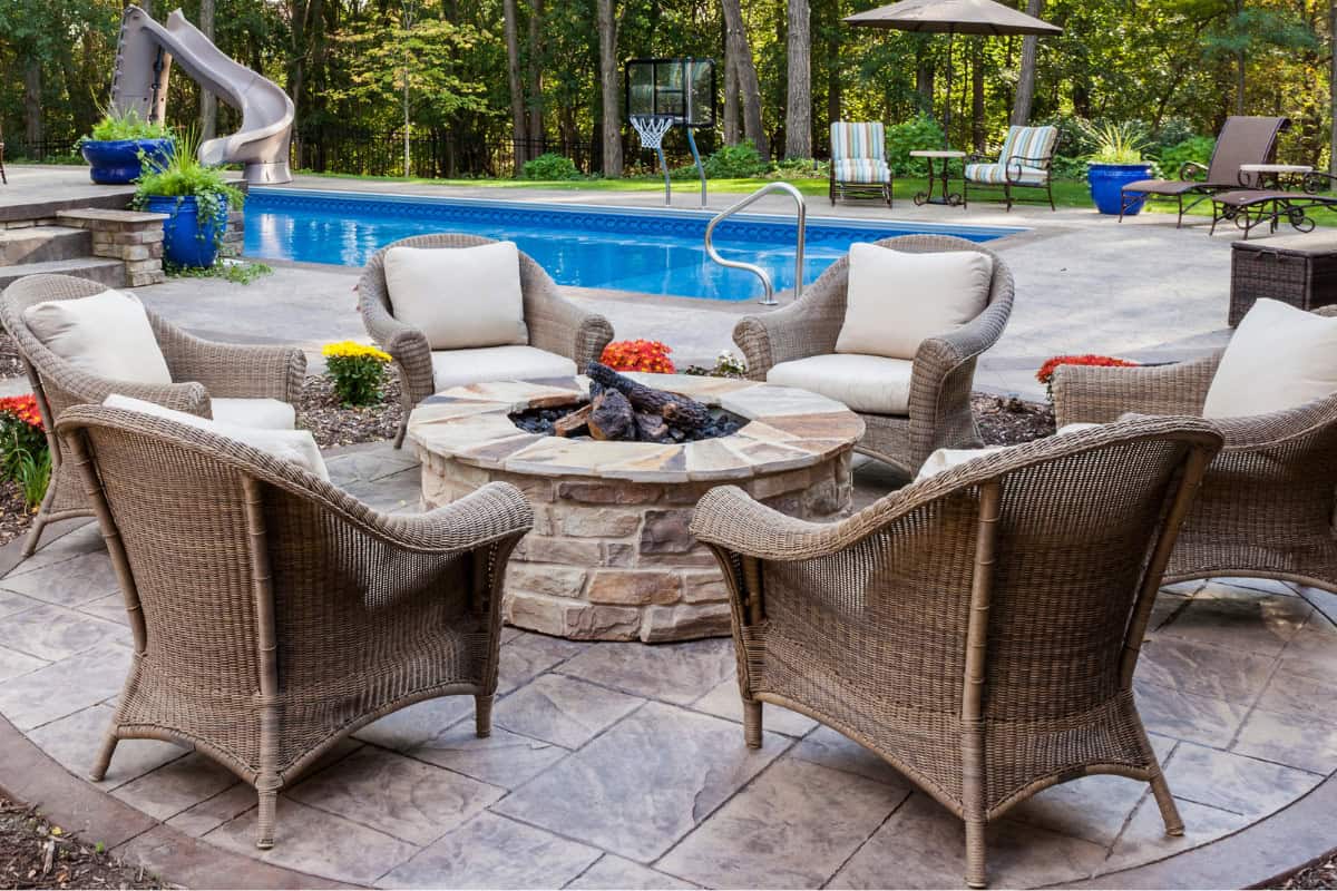 Image of a gas fire pit poolside for a blog post covering fire pit seating ideas.