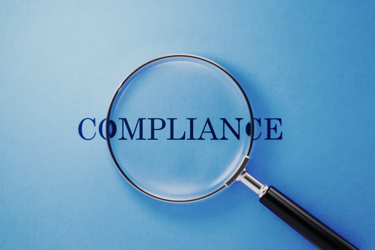 city-fire-pit-rules-placement-compliance Image of a magnifying glass looking at the word "compliance" in the center of the page.