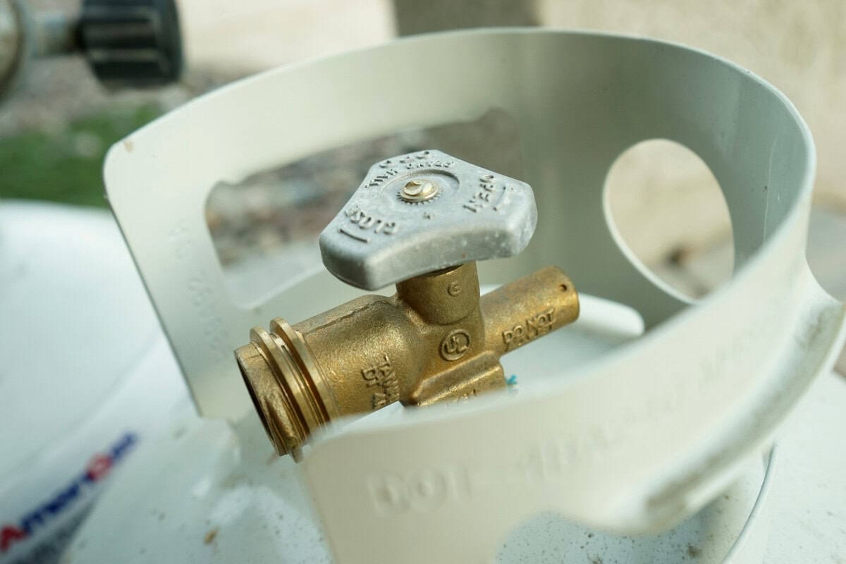 Bronze gas valve inside a white propane tank, ready for outdoor heating or cooking appliances at backyard parties.