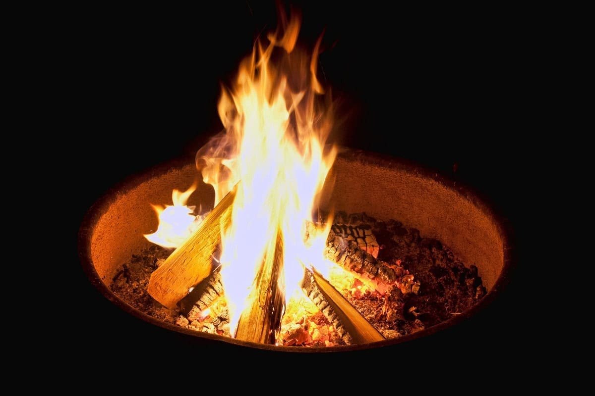 Image of a fire pit fire at night for a blog post about how to put out a fire pit.