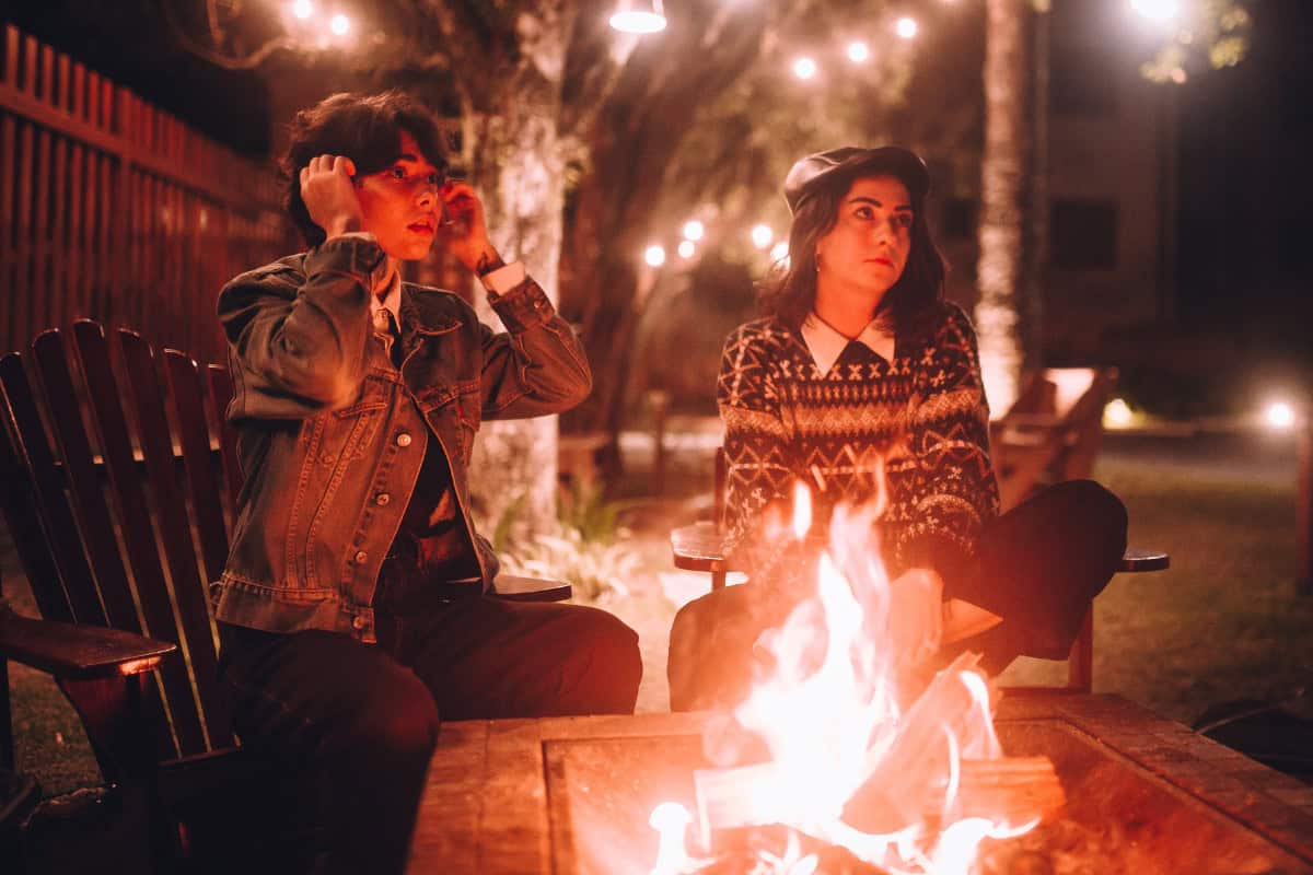 Image of two people around a fire pit at night.