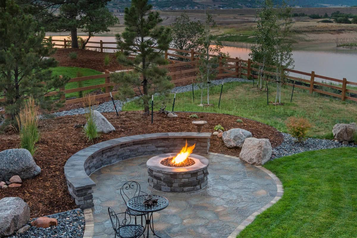 Image of a gas fire pit on a stone patio next to a retaining pond for a blog post covering fire pit home value ROI.