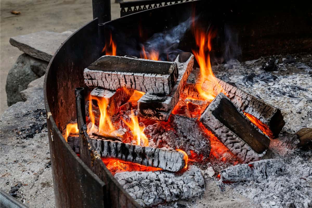 Image of a small fire in a large fire pit for a blog post covering how to dispose of fire pit ash.