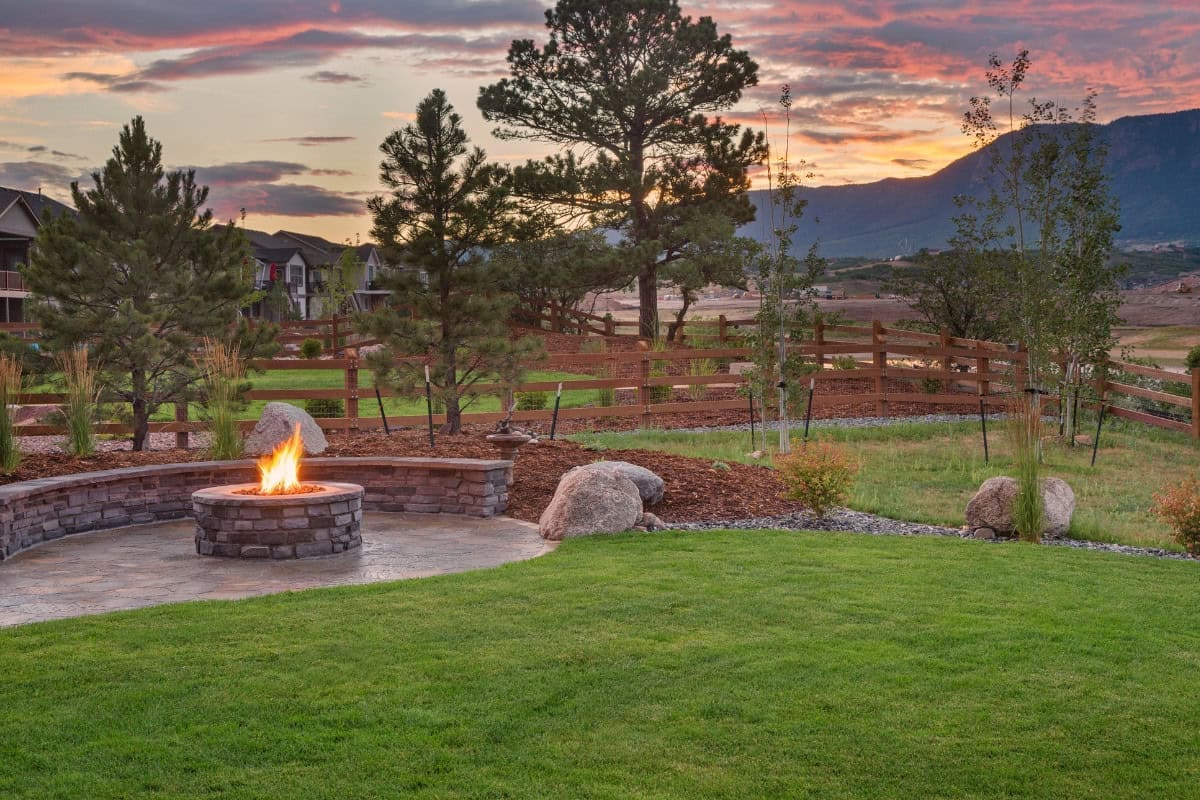 Image of a yard with a block fire pit at the left of image.