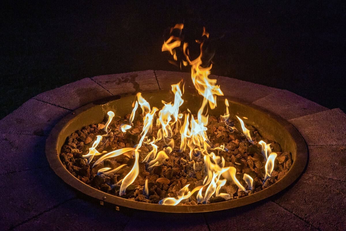 Image of a burning gas fire pit at night.