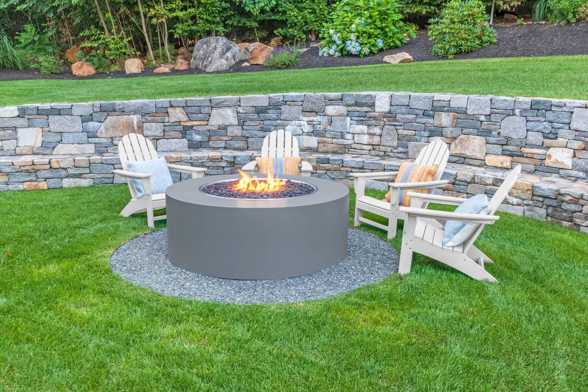 Image of a fire pit and retaining wall in a backyard for a blog post asking "what size fire pit should I buy?"
