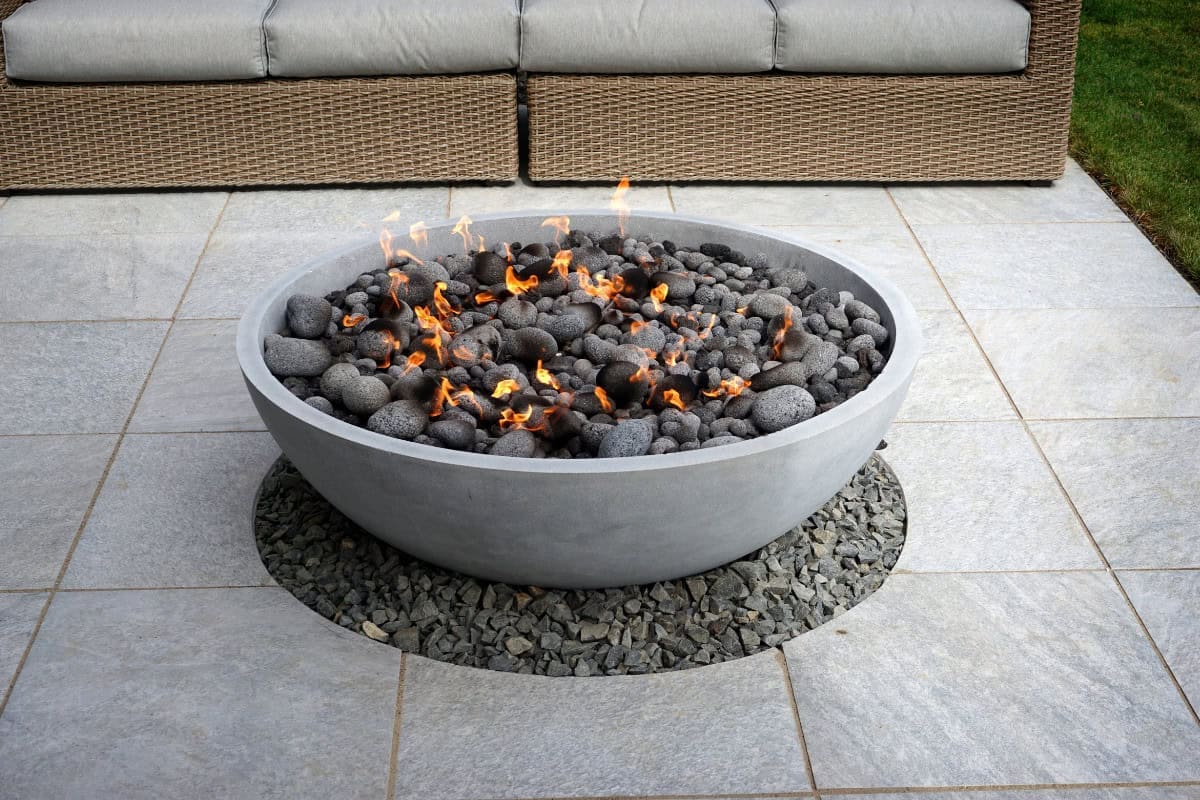 Image of a natural gas fire pit bowl on a hardscape patio.
