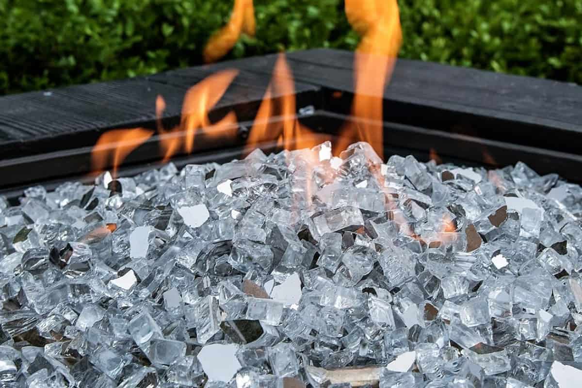 Image of a square gas fire pit with clear fire glass for a blog post answering the question, "what is fire pit media?"