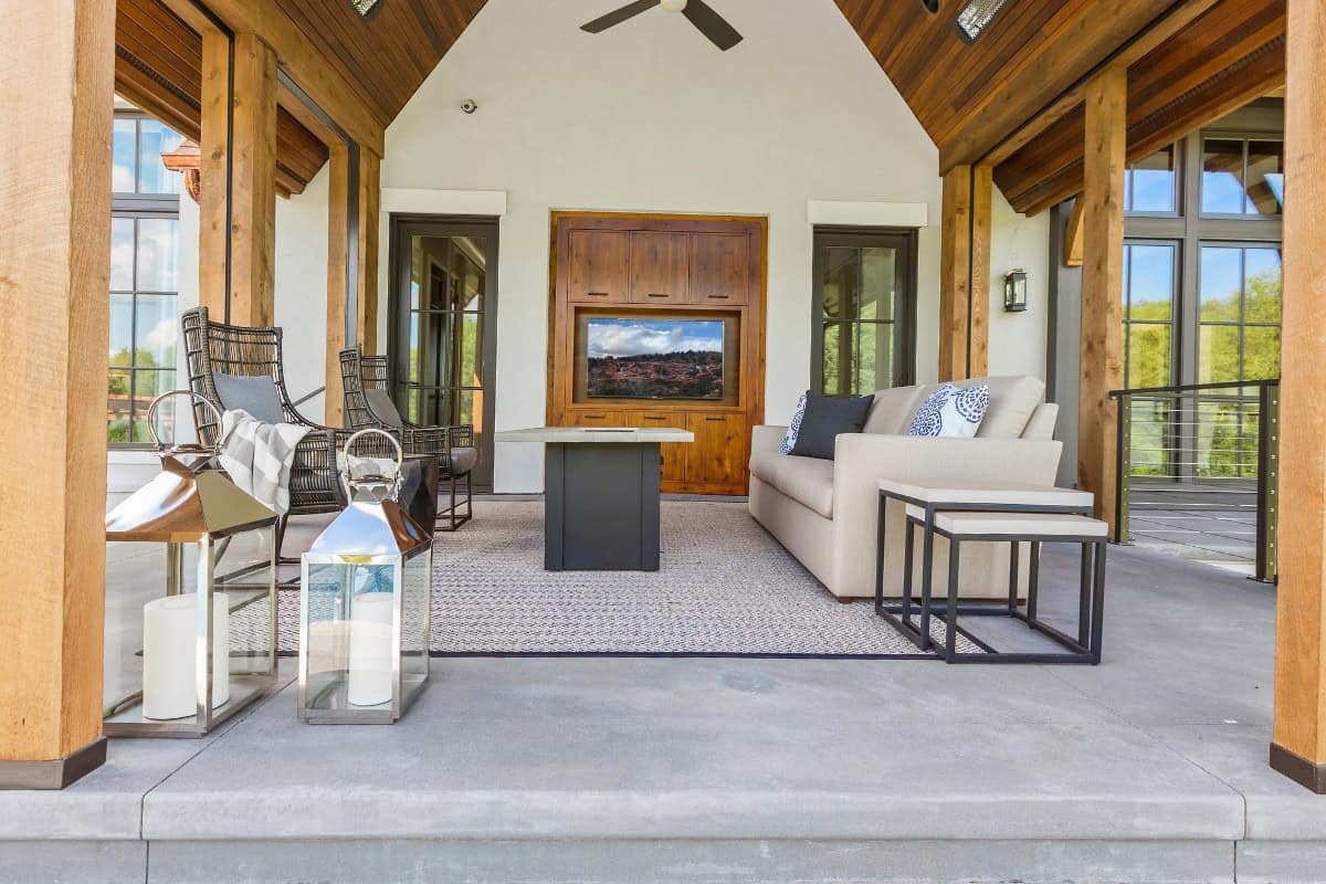 Modern outdoor lounge with cozy seating, TV, and fireplace in backyard patio area.