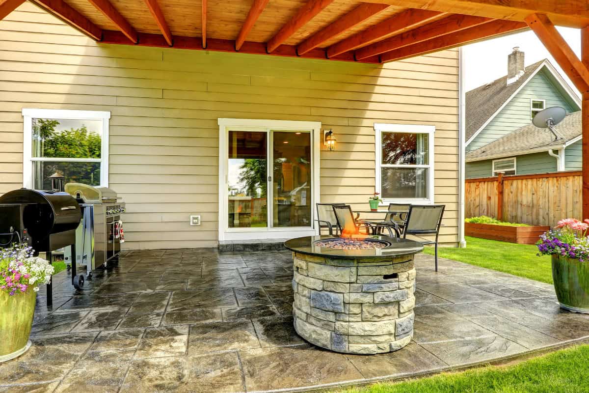 Beautiful backyard patio with a stone fire pit, outdoor seating, and a built-in grill, perfect for outdoor gatherings and relaxing evenings.