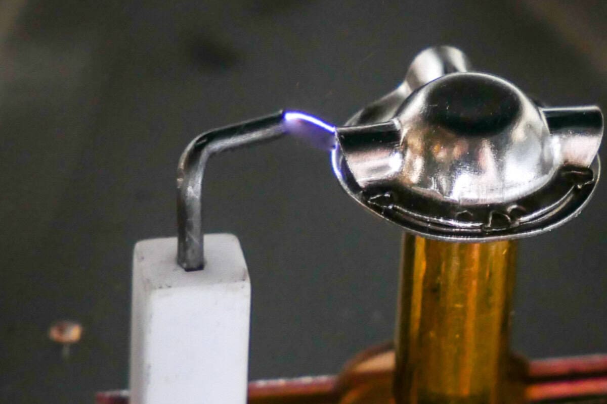 A propane torch igniting a small metal object for wood burning or pyrography art in a backyard setting.