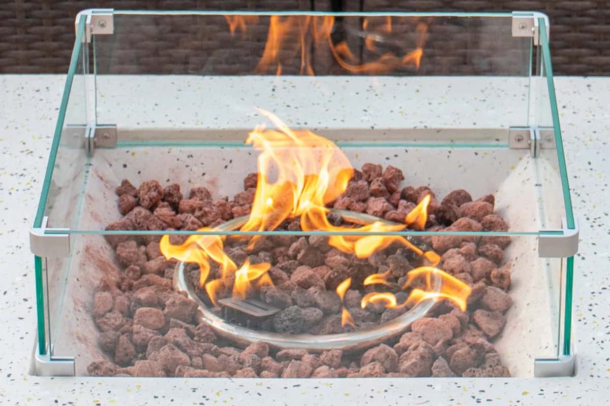 Outdoor fire pit with glass enclosure and propane burner, perfect for backyard heating and ambiance.