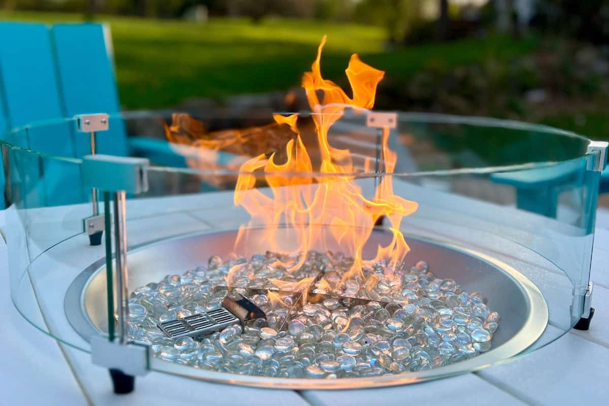 Cool fire pit with glass beads and a protective glass shield for outdoor backyard gatherings.